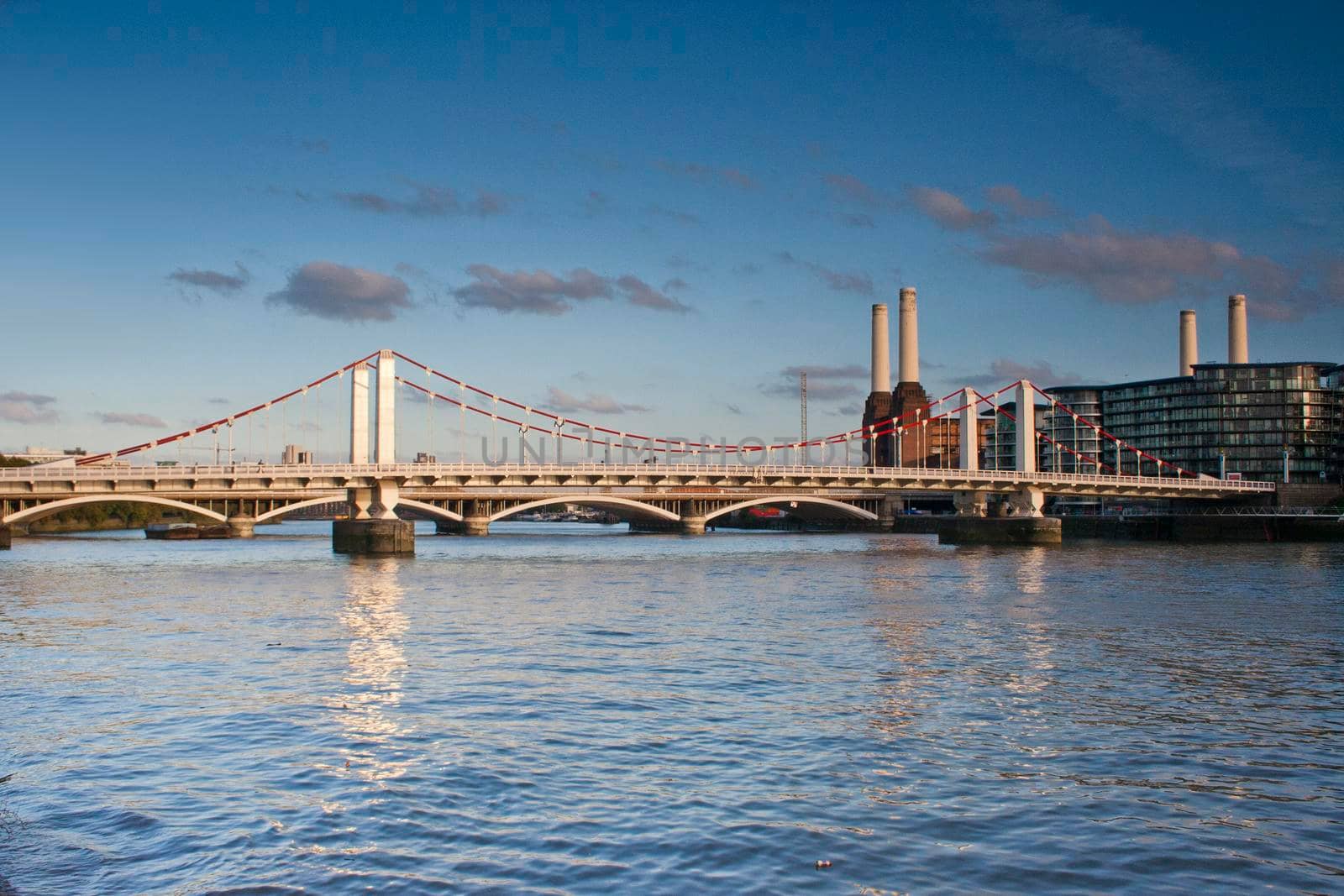 The River Thames with the Grosvenor Rail Bridge and Battersea Power Station in the background with blue sky and white clouds