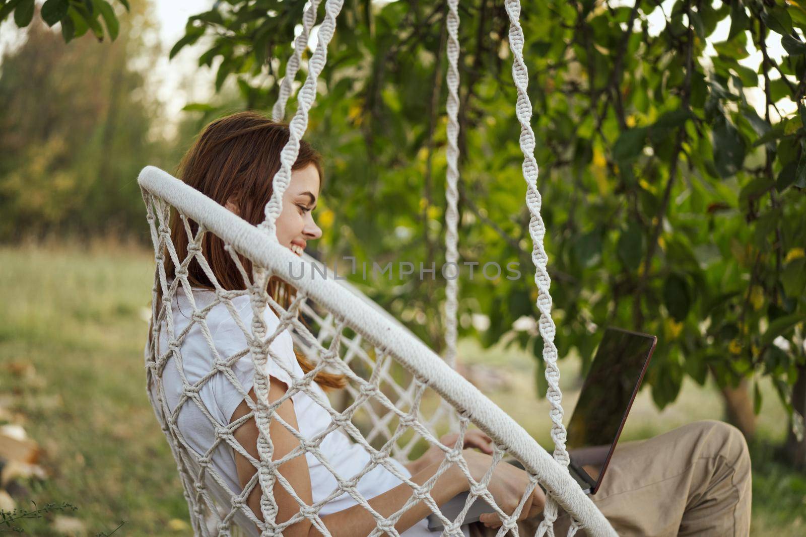 woman with laptop outdoors resting in hammock internet. High quality photo