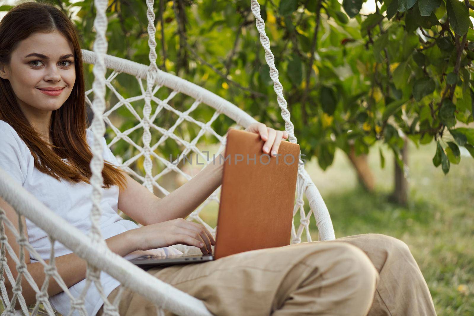 cheerful woman outdoors in hammock with laptop rest. High quality photo