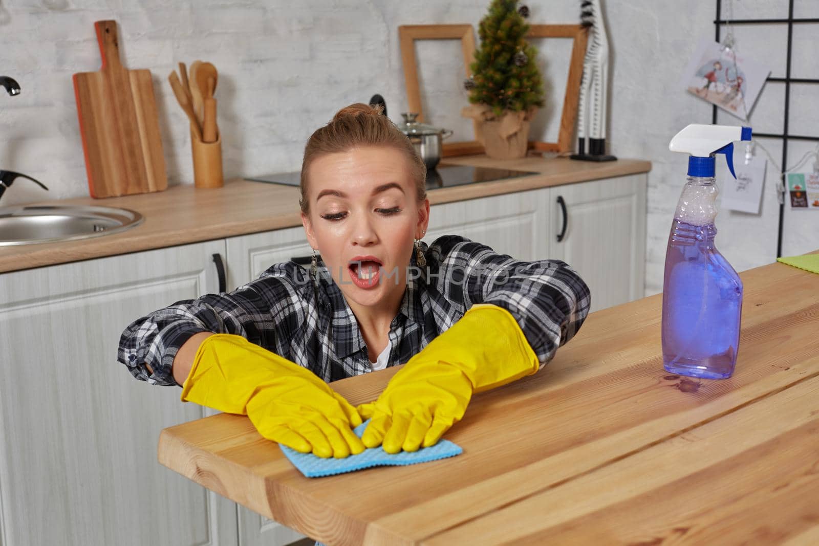 Young woman in protective gloves wipes a table in the kitchen with a rag. Fatigue. Household, cleaning and people concept
