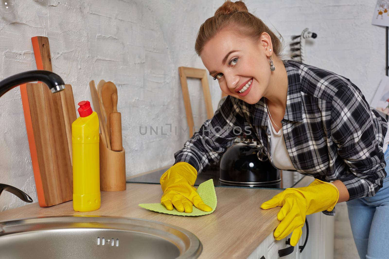 Hand cleaning. Young housewife woman washing sink in kitchen. Young woman washing manually, by hand, wearing yellow cleaning rubber gloves.