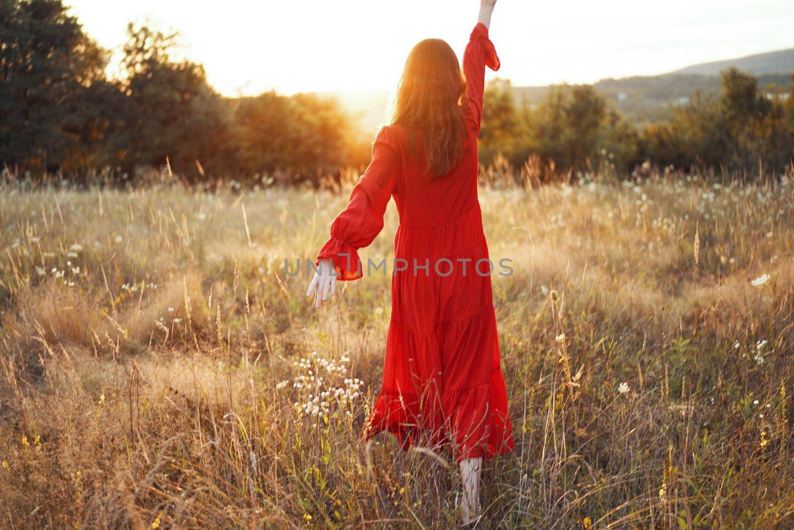 woman in red dress in the field walk freedom landscape. High quality photo