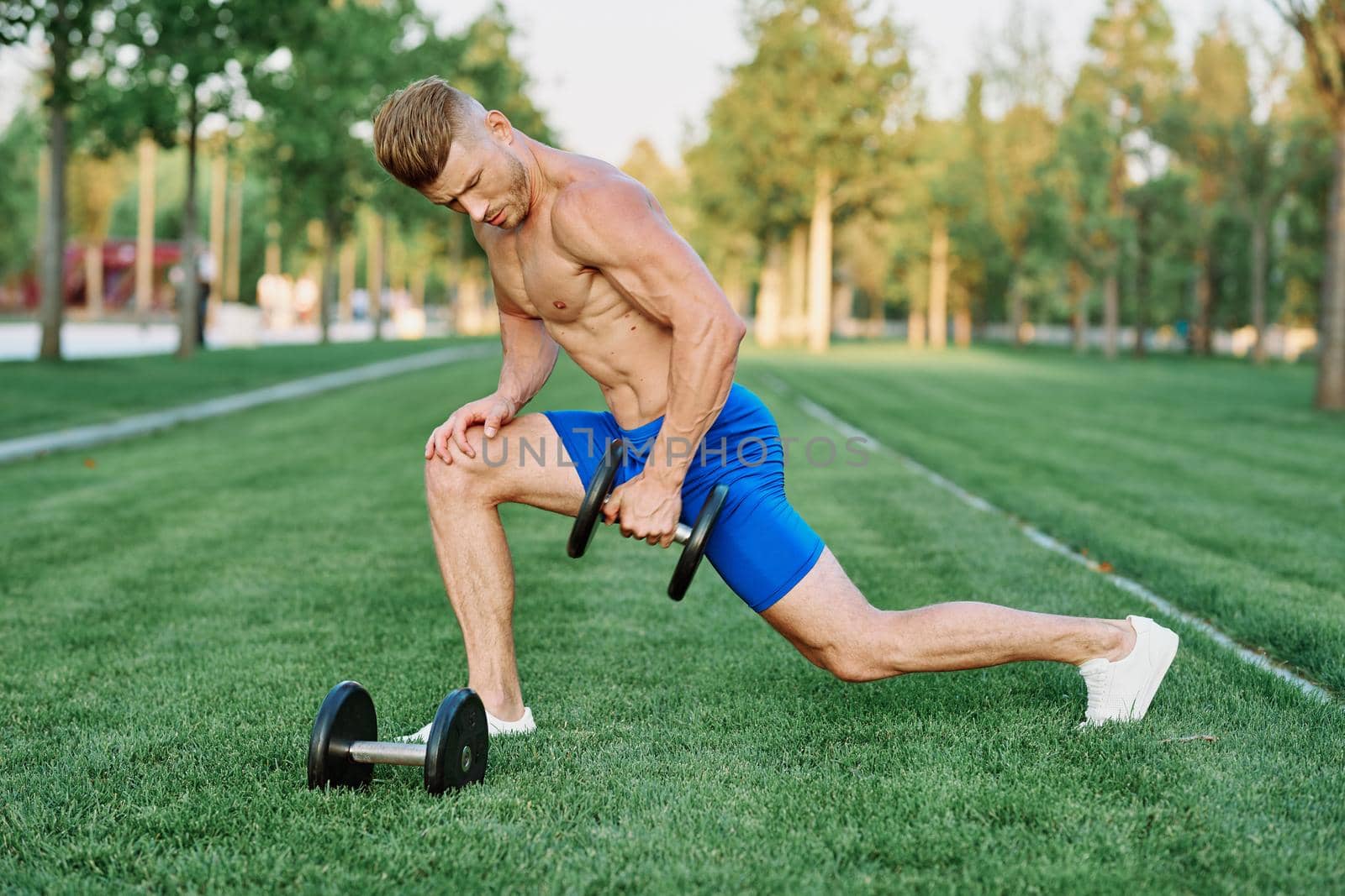 sporty man with pumped up body in park workout exercise. High quality photo