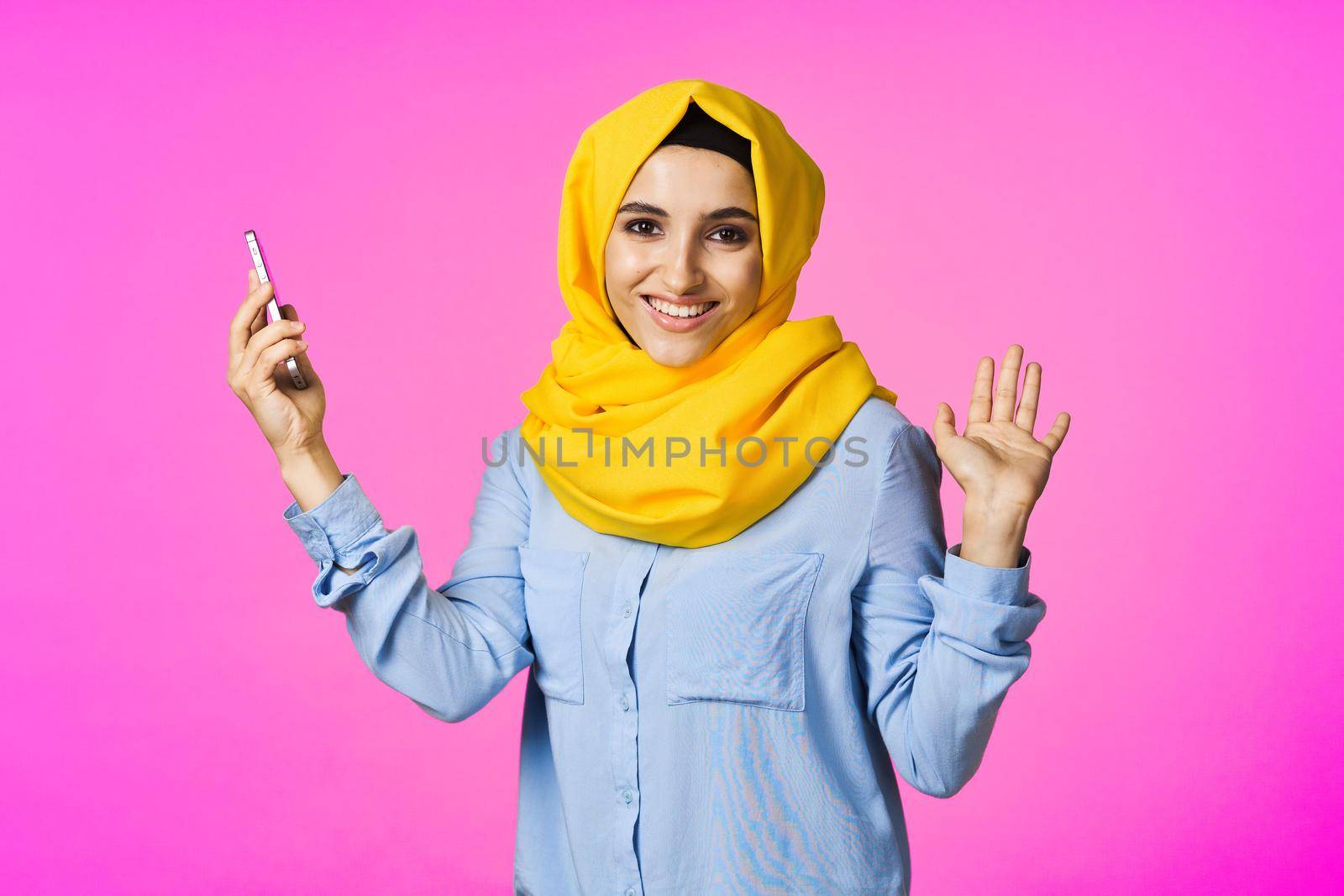 cheerful woman in a yellow hijab with a phone in her hands communication technology. High quality photo