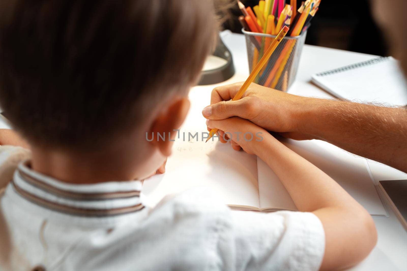 Little boy writing something in his notebook close up