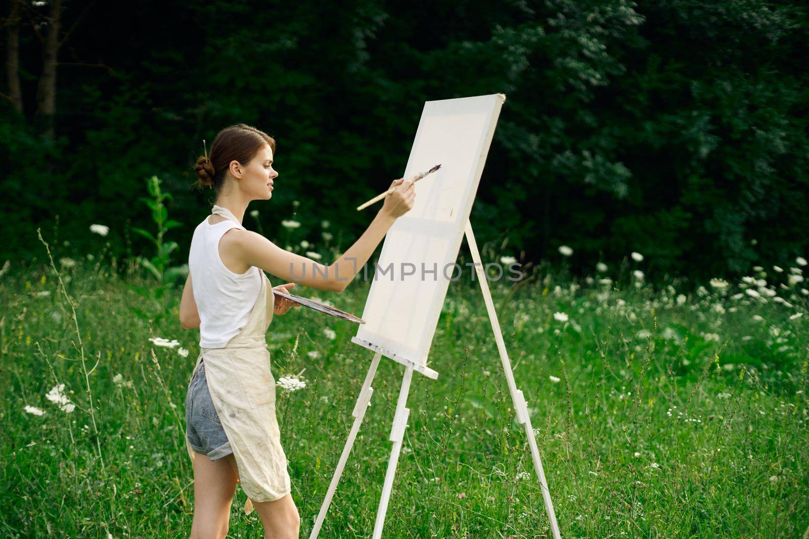 woman artist with palette of paints drawing easel nature hobby. High quality photo