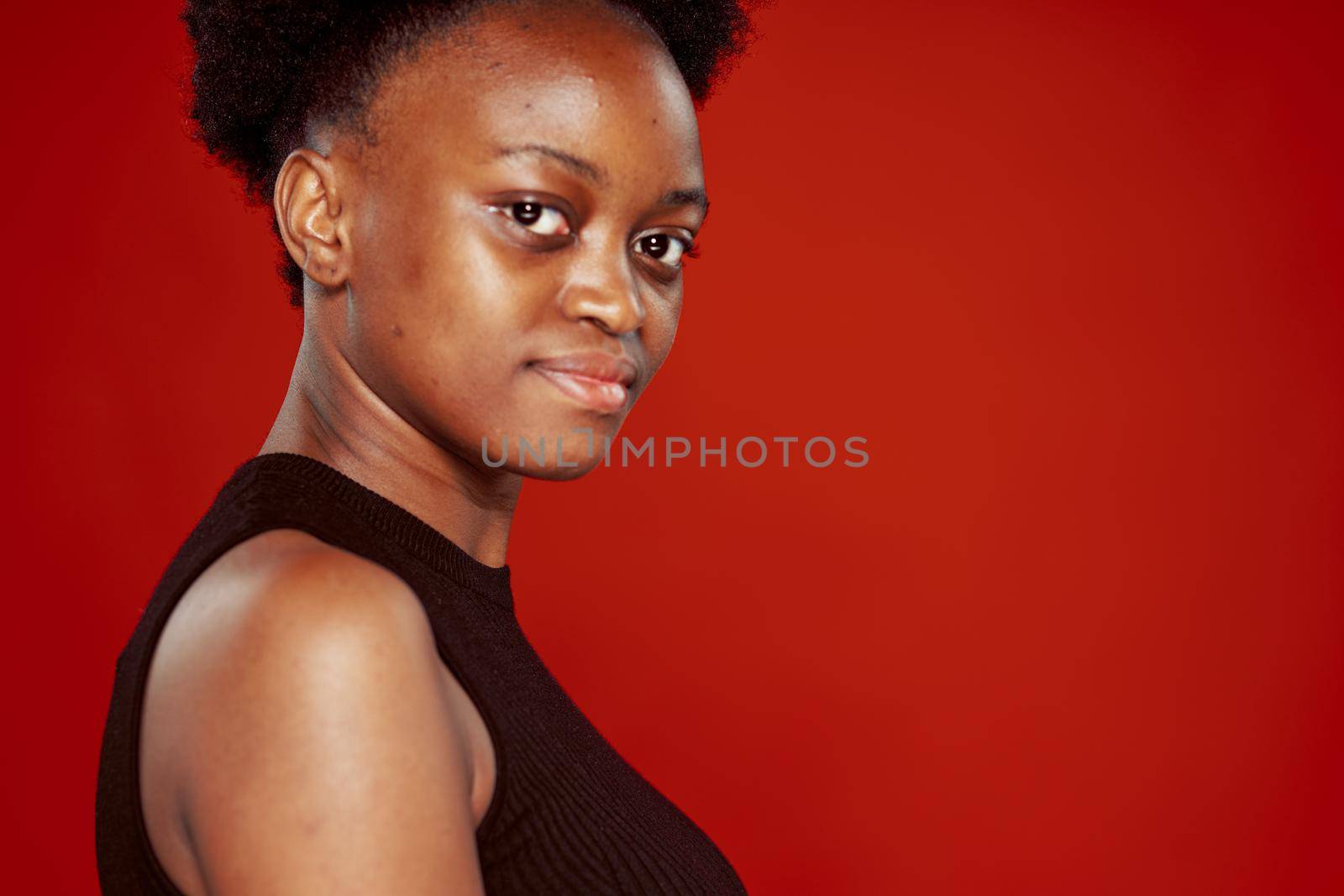 curly african woman in black t-shirt red background. High quality photo