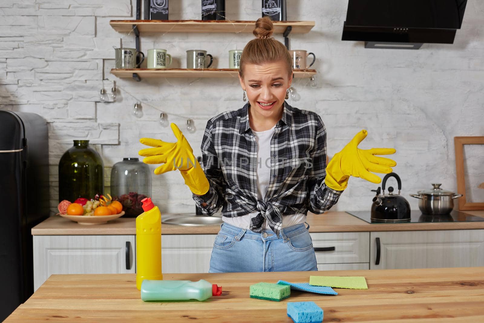 Young woman wearing apron sitting with heap of cleaning sponges indoors. Household, cleaning and people concept