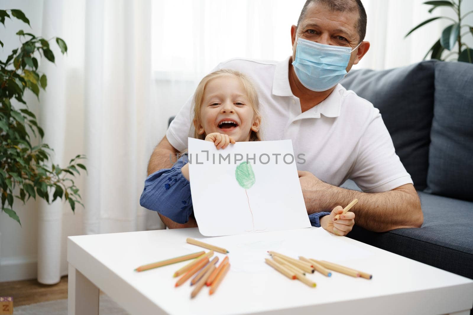 Grandfather and granddaughter drawing together in living room at home