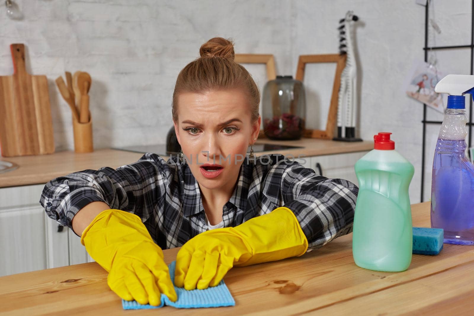 Young woman in protective gloves wipes a table in the kitchen with a rag. Fatigue. Household, cleaning and people concept