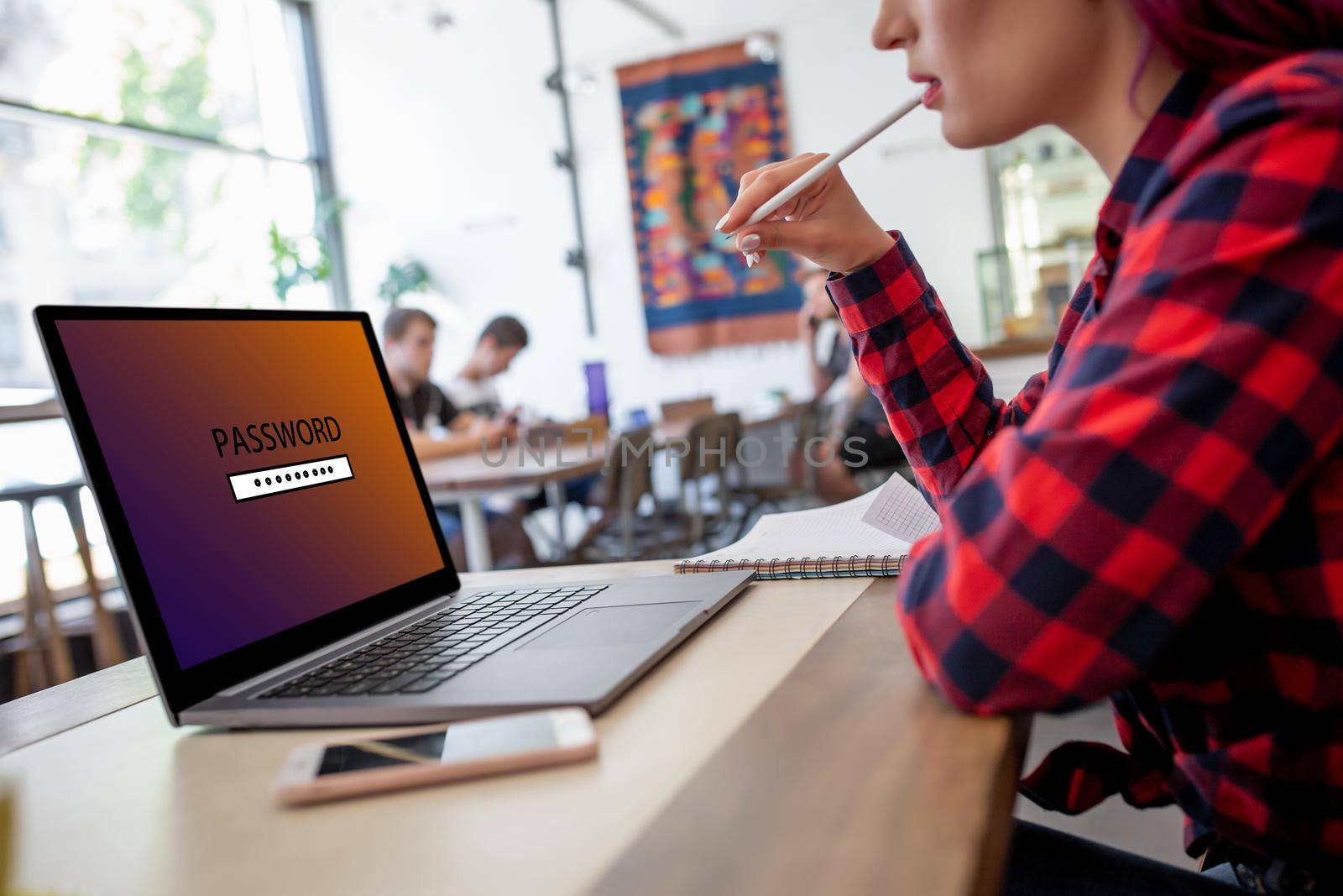 Side view of a young woman sitting in cafe, hand typing laptop computer with password login on screen. Cyber security concept