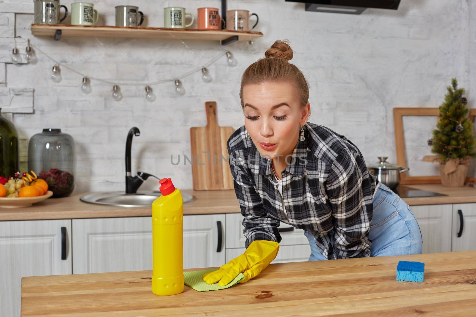 Household, cleaning and people concept - happy woman or housewife in rubber gloves wiping table with microfiber cloth at home kitchen.
