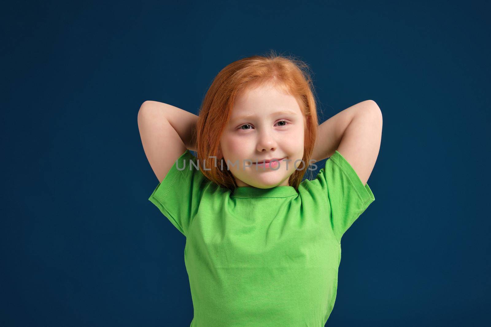 close up photo of little redhead emotional girl in green t-shirt posing before camera.She is tired and wants to sleep, yawning and stretching