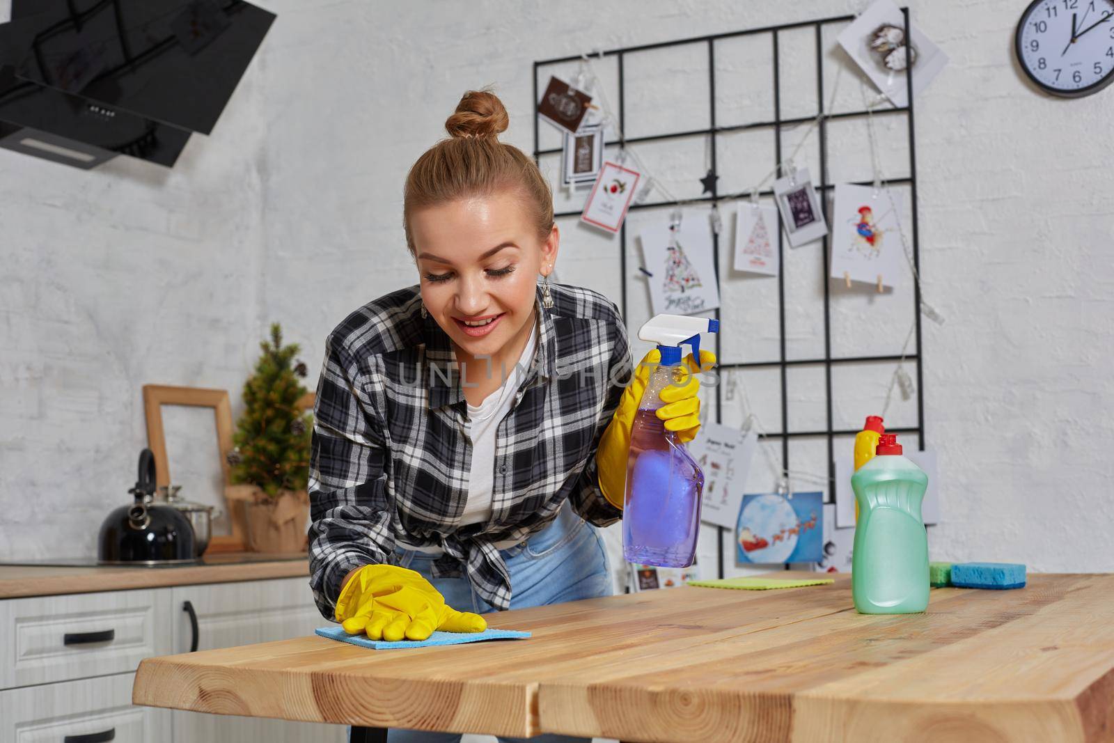 Household, cleaning and people concept - happy woman or housewife in rubber gloves wiping table with microfiber cloth at home kitchen.