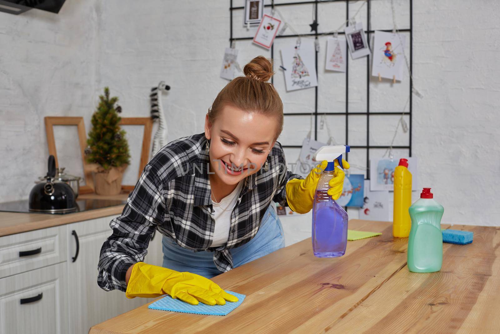 Household, cleaning and people concept - happy woman or housewife in rubber gloves wiping table with microfiber cloth at home kitchen.