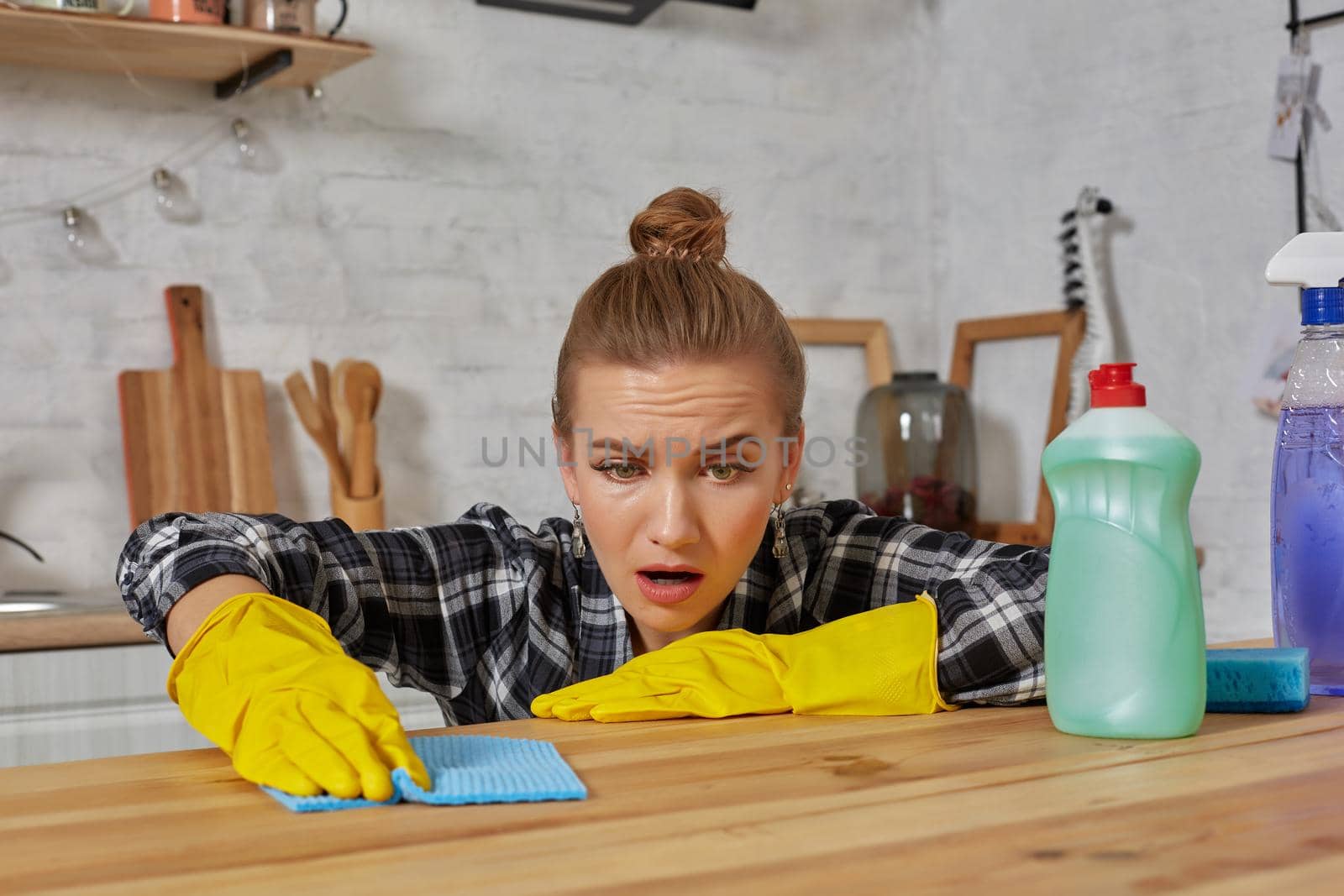 Young woman in protective gloves wipes a table in the kitchen with a rag. Fatigue. Household, cleaning and people concept