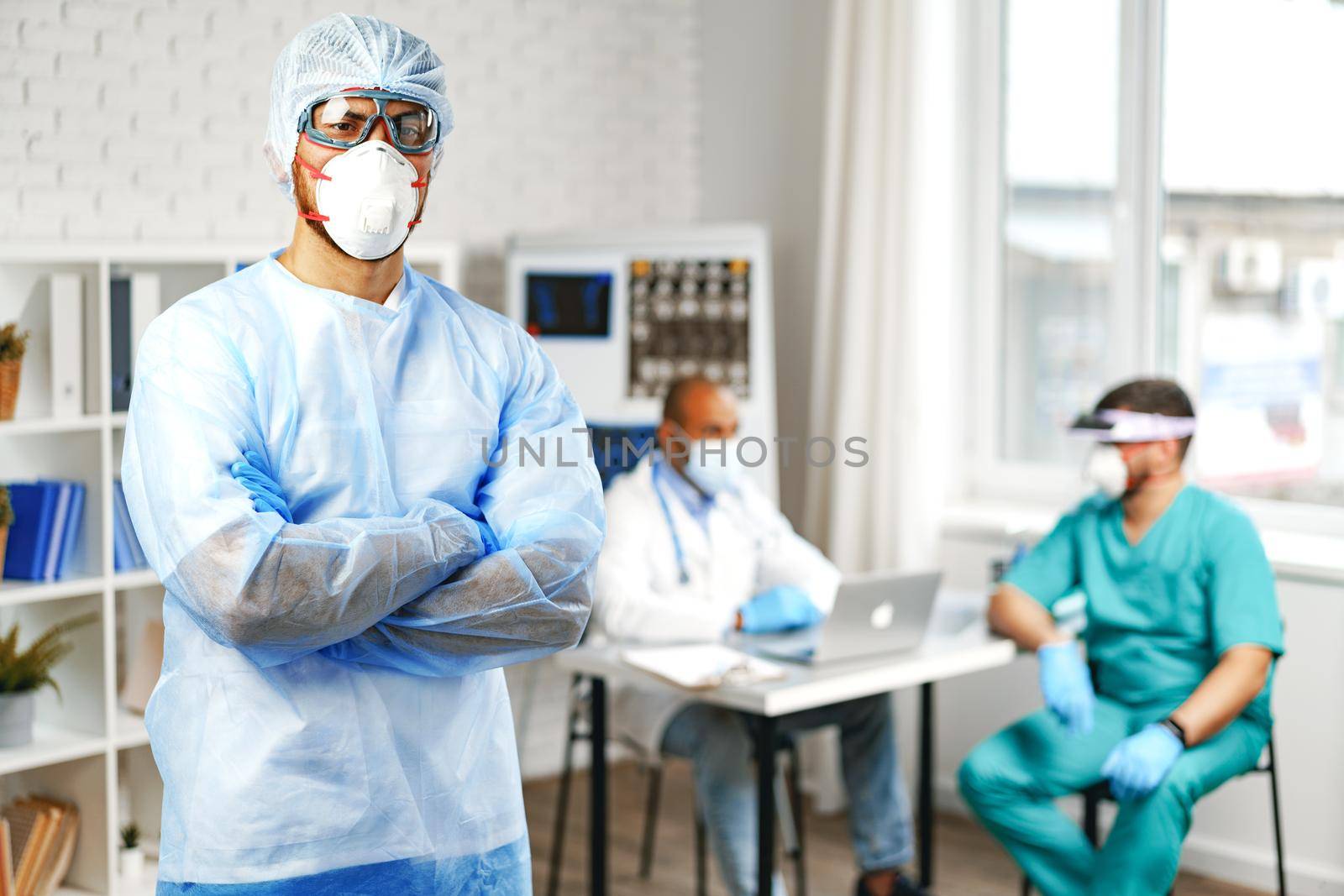 Male doctor in protective medical gown standing in hospital cabinet by Fabrikasimf