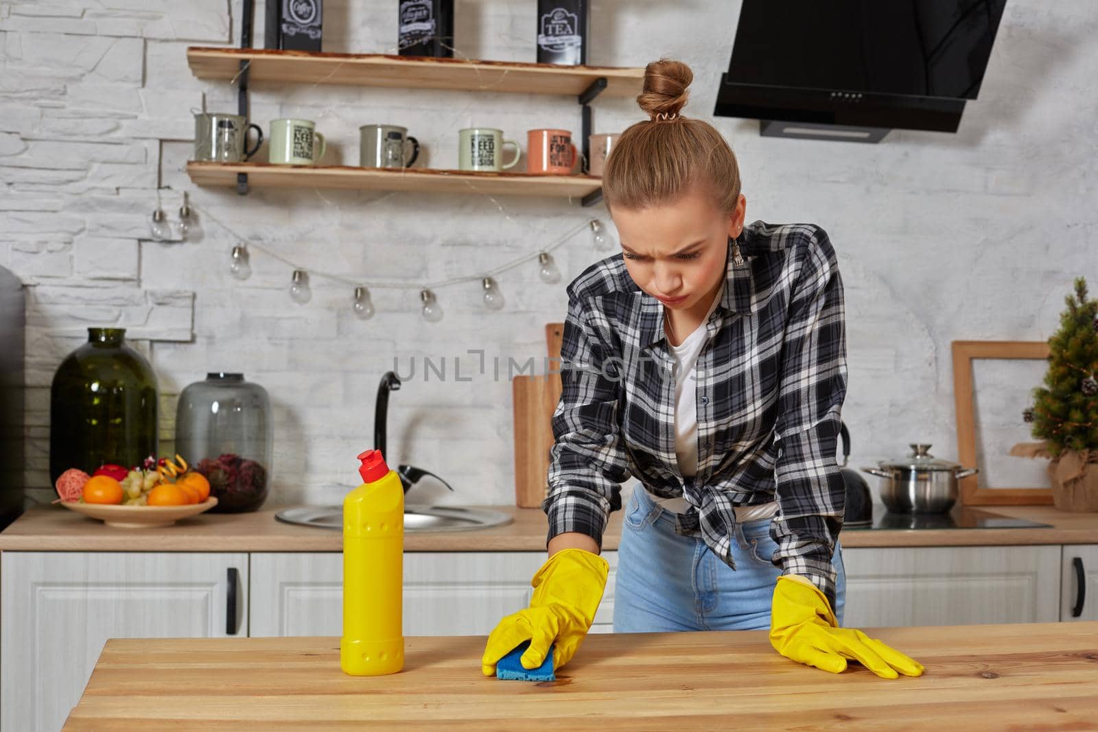 Young woman in protective gloves wipes a table in the kitchen with a rag. Fatigue. Household, cleaning and people concept
