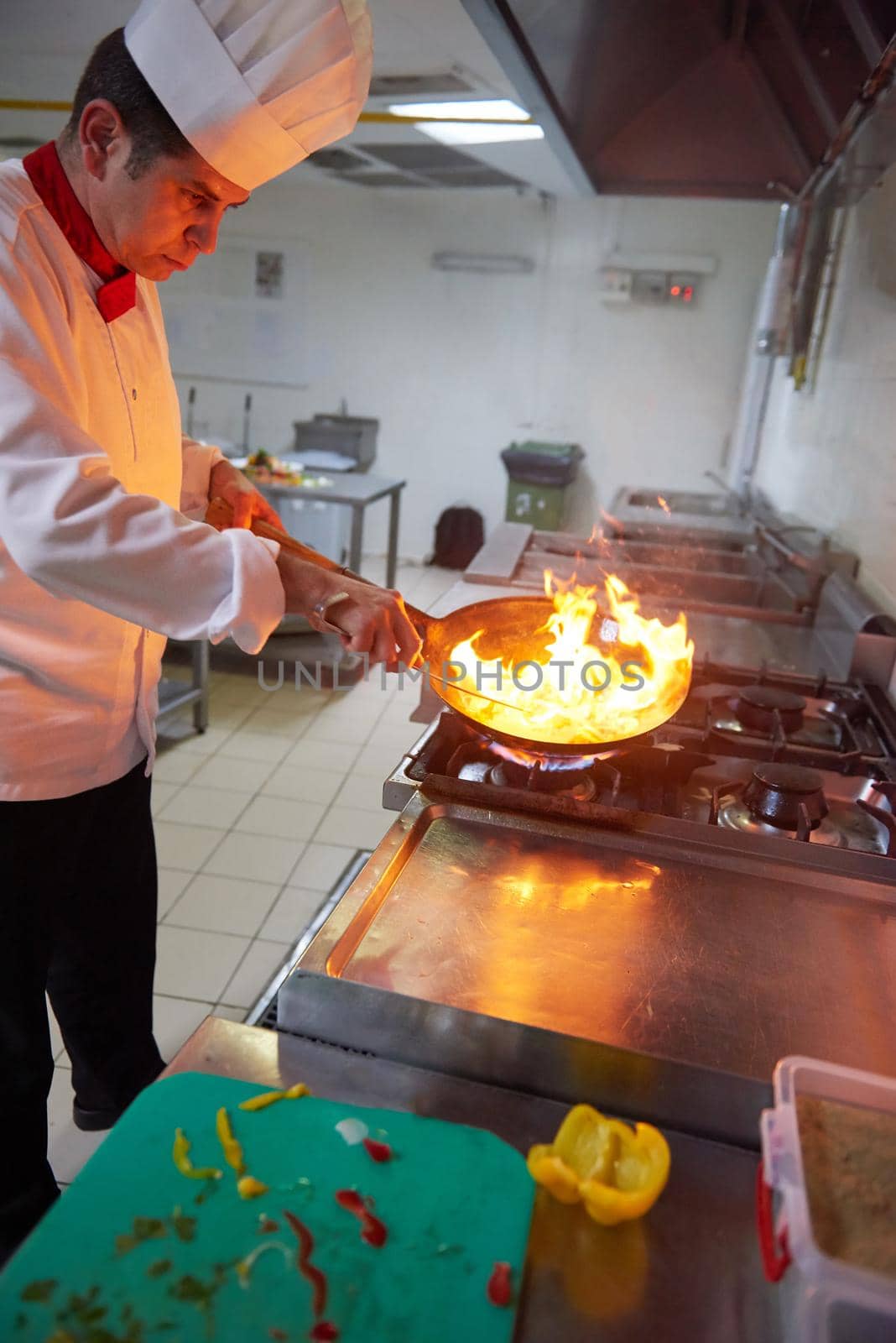chef in hotel kitchen prepare food with fire by dotshock