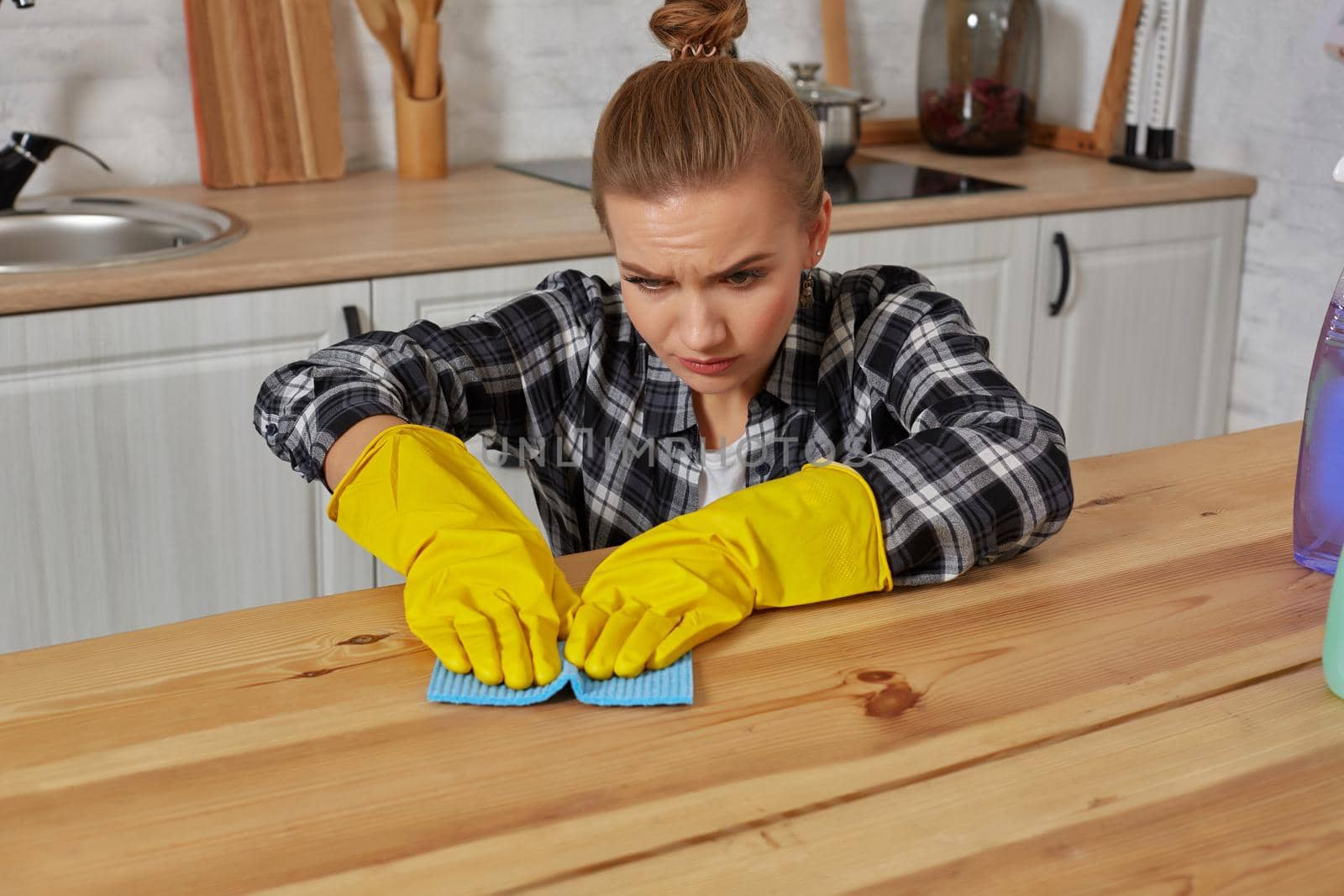 Young woman in protective gloves wipes a table in the kitchen with a rag. Fatigue. Household, cleaning and people concept