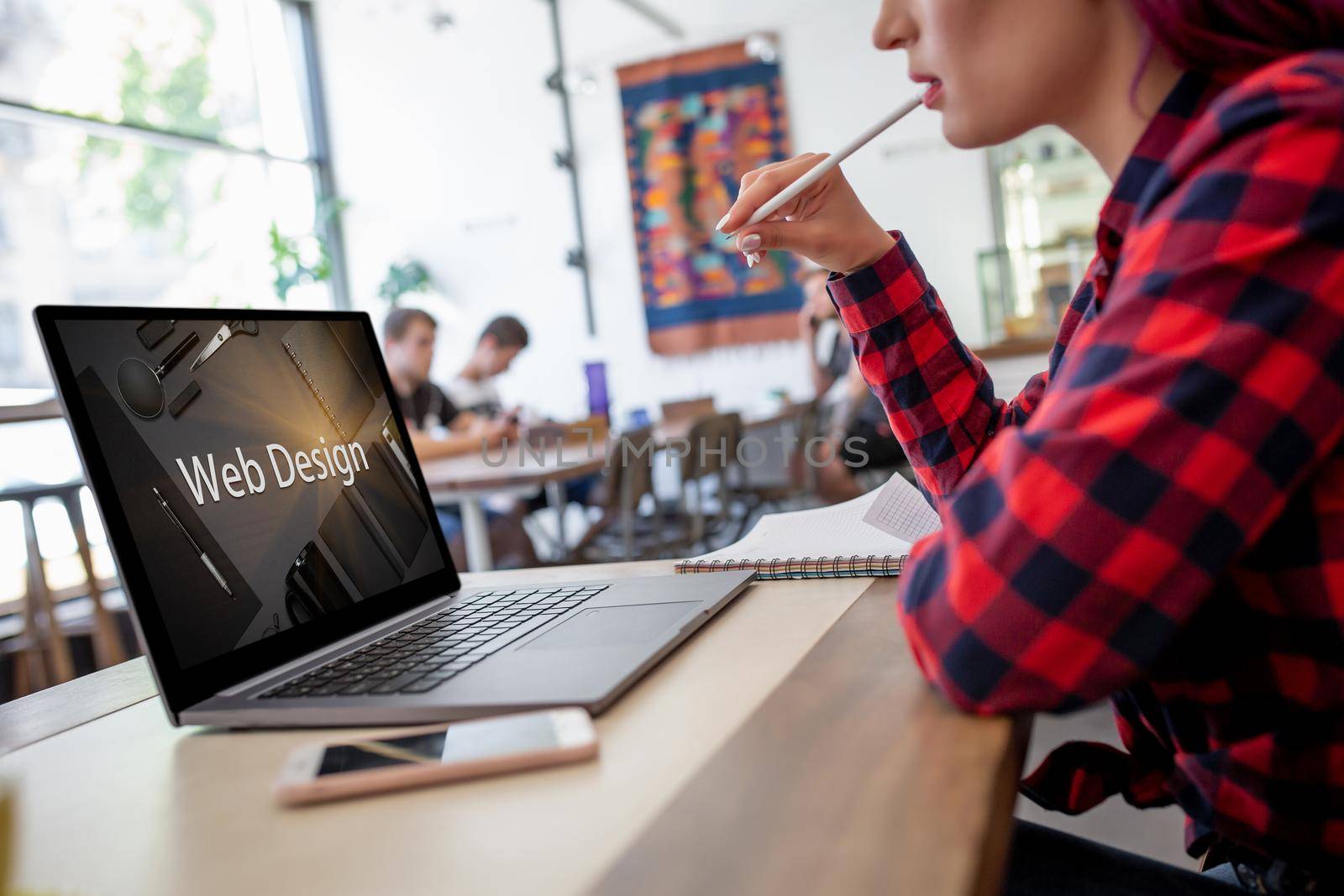 Cropped shot view of young woman working on laptop computer while sitting in modern cafe bar interior, female freelancer using net-book for remote job during morning breakfast in coffee shop. Design. Web design