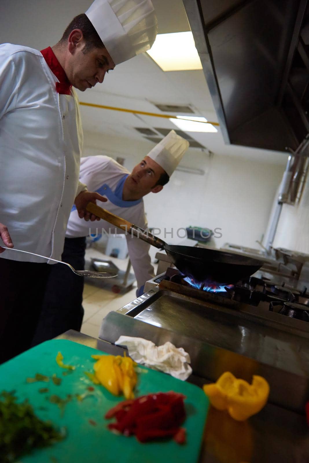 chef in hotel kitchen prepare food with fire by dotshock