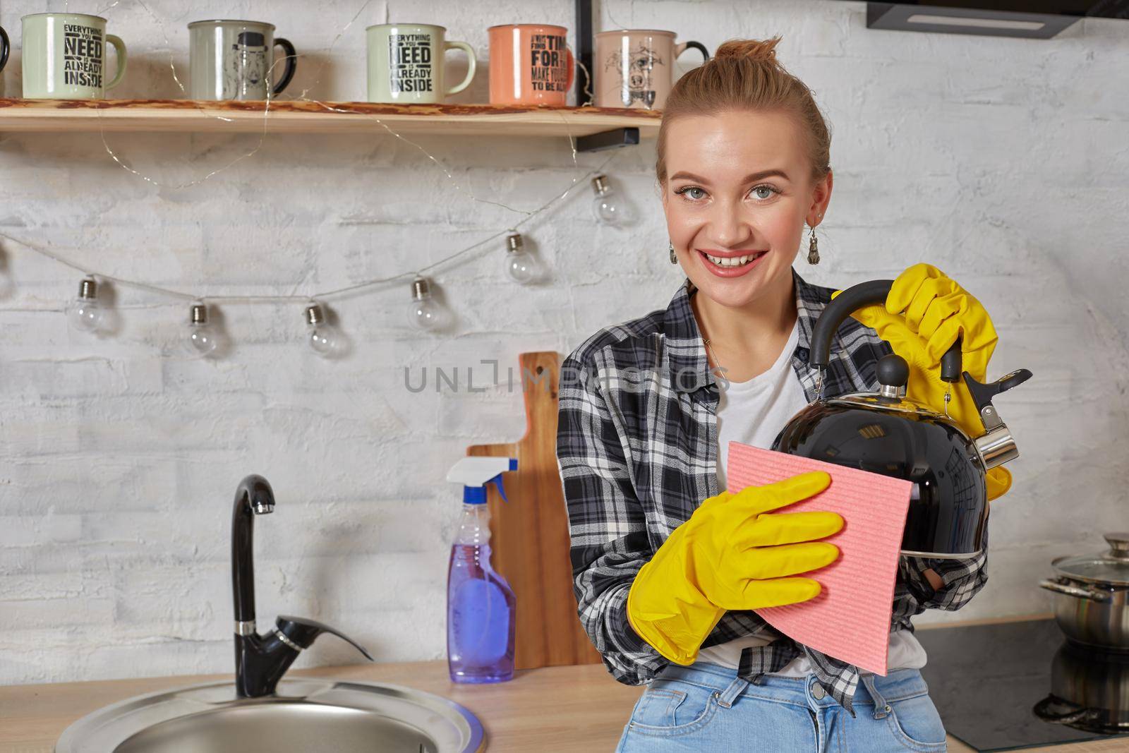 Domestic service and housekeeping concept, happy blonde lady cleaning kitchen kettle, close-up of hands in rubber gloves holding spray