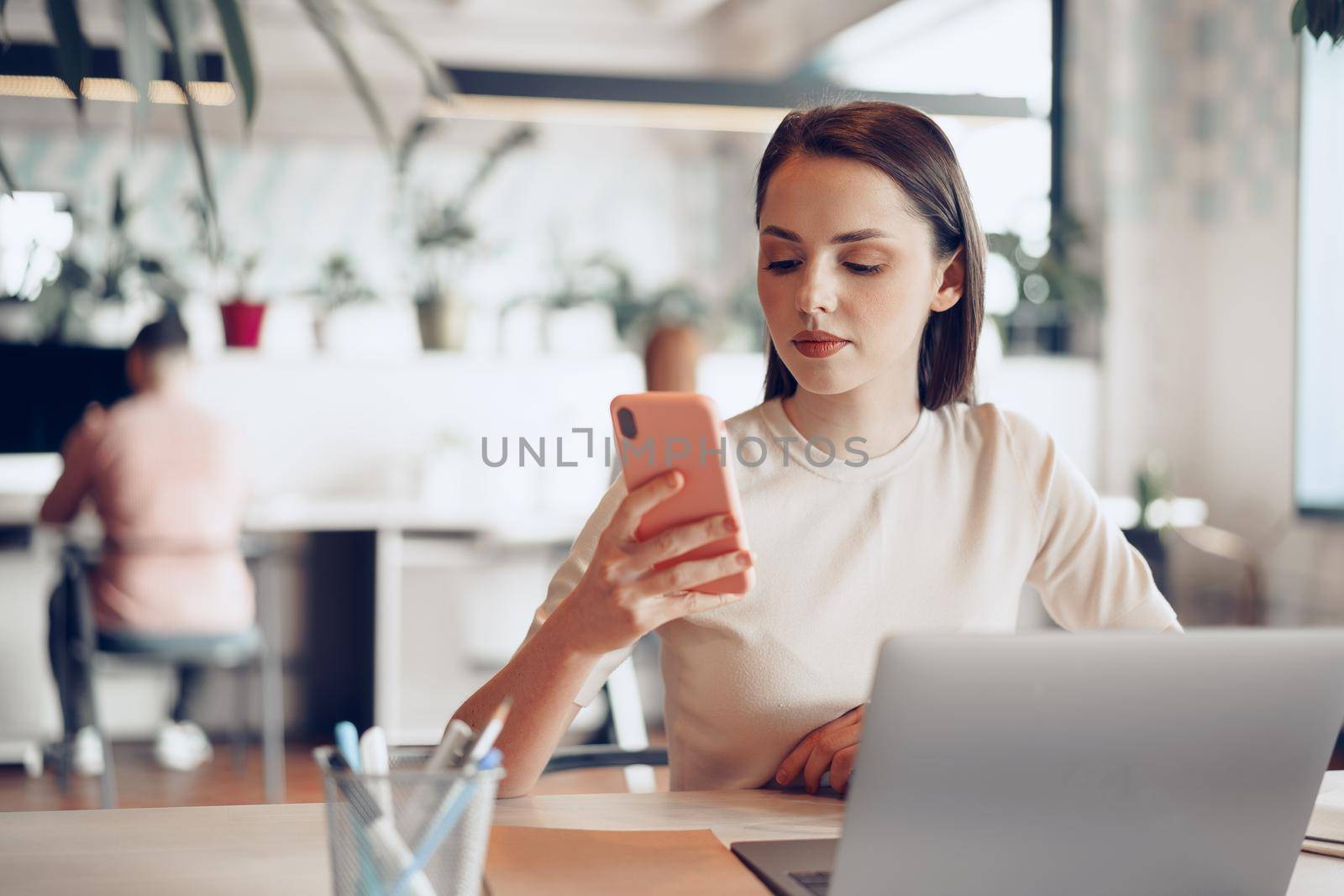 Young attractive businesswoman using her smartphone in office close up
