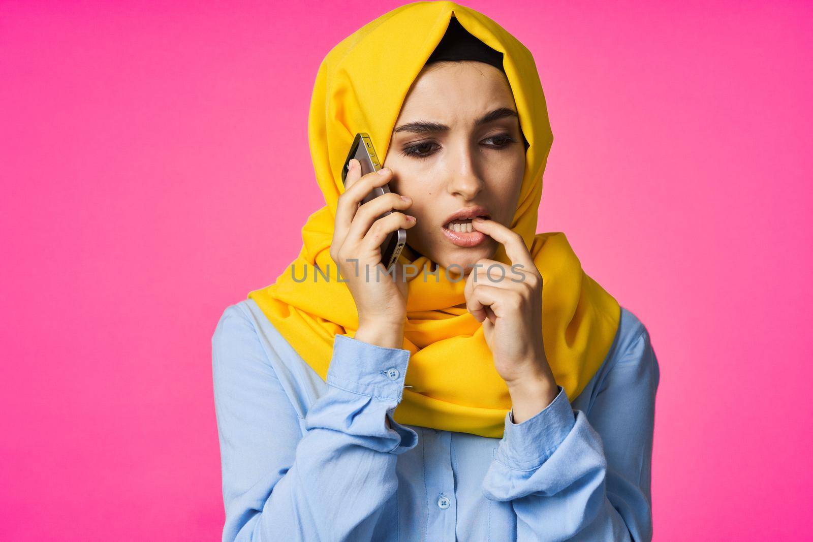 Muslim woman wearing hijab telephone communication technology pink background. High quality photo