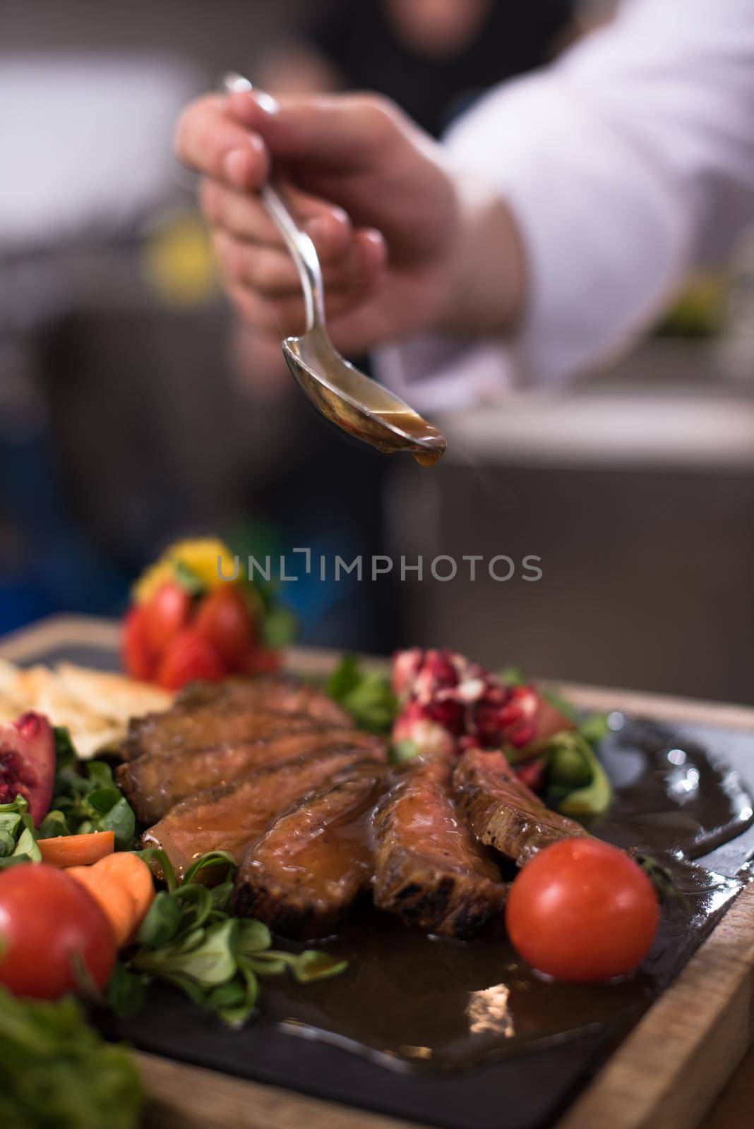 Chef hand finishing steak meat plate with Finally dish dressing and almost ready to serve at the table