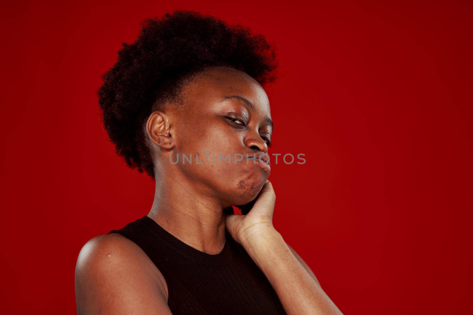 curly african woman in black t-shirt red background. High quality photo