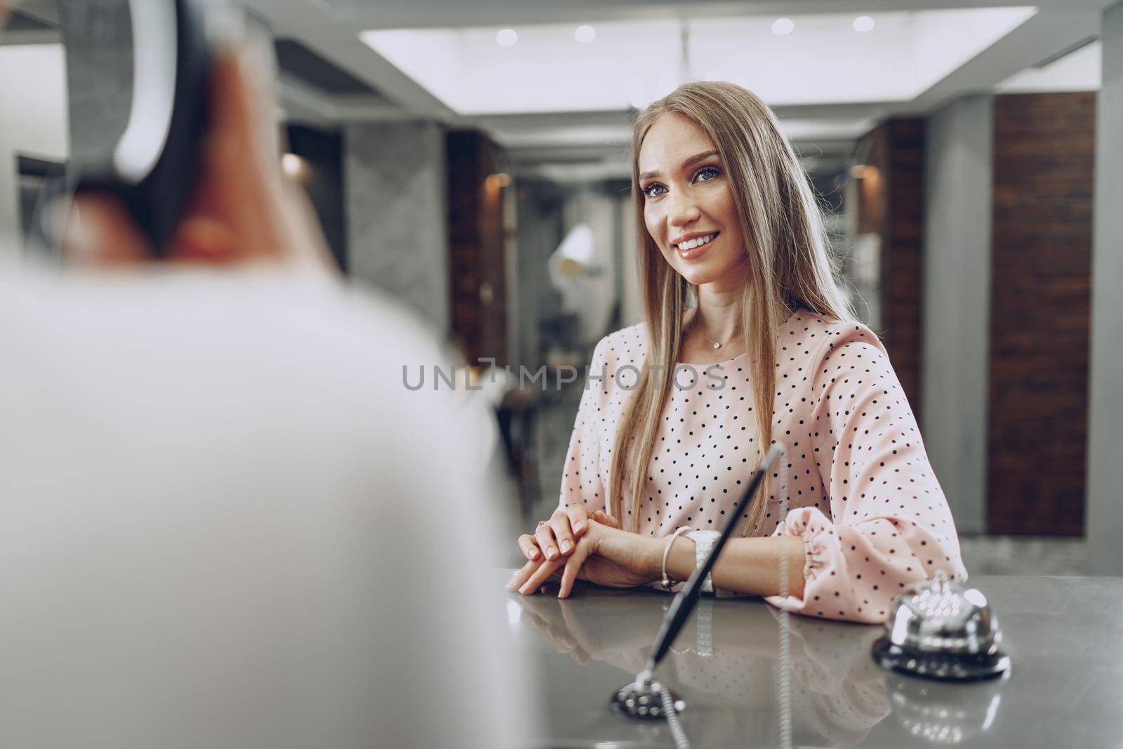 Blonde woman hotel guest checking-in at front desk in hotel close up