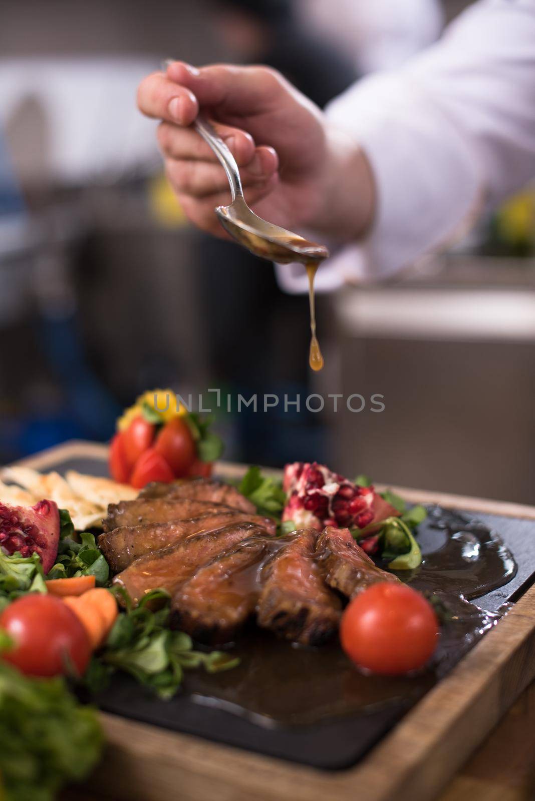 Chef hand finishing steak meat plate with Finally dish dressing and almost ready to serve at the table