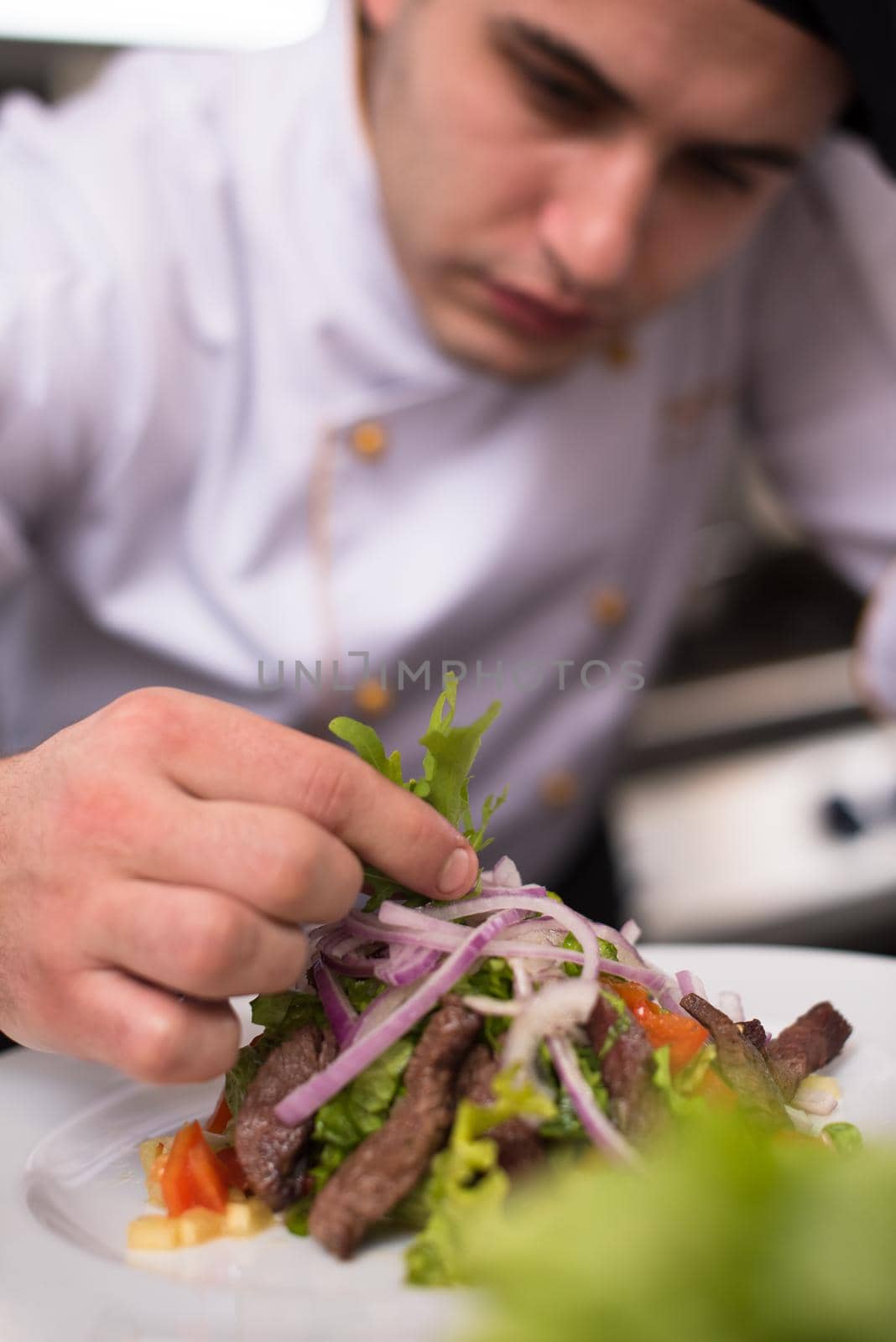 cook chef decorating garnishing prepared meal dish on the plate in restaurant commercial kitchen