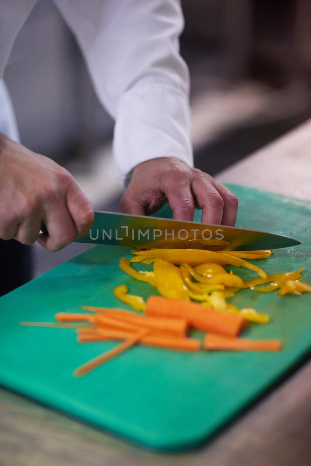 chef in hotel kitchen  slice  vegetables with knife by dotshock