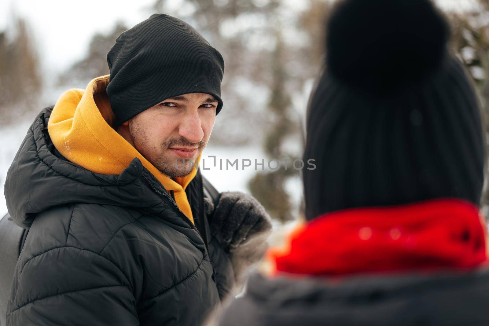 Close up photo of young couple in warm clothes standing together in a winter park