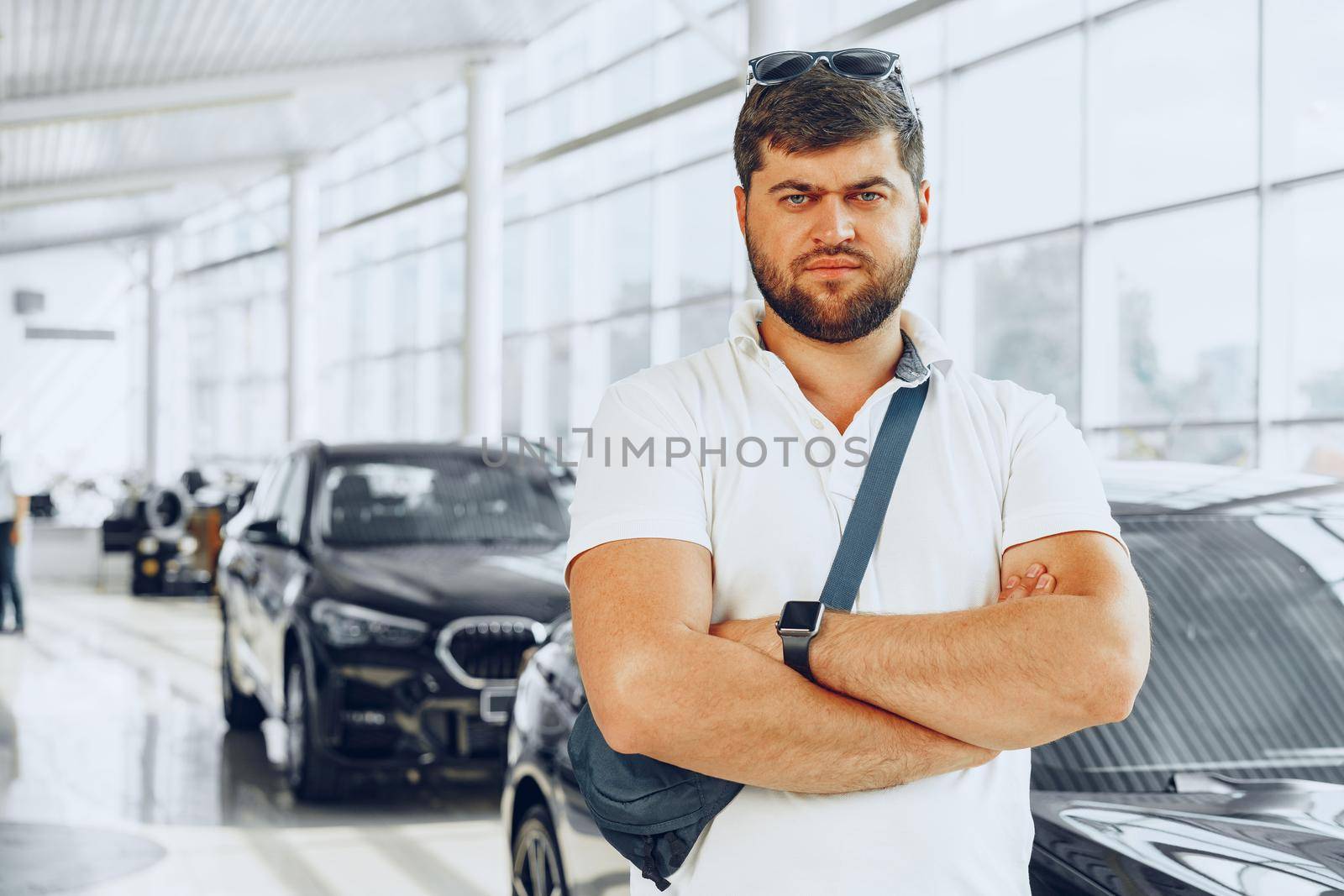 Serious young man on blurred car salon background, portrait