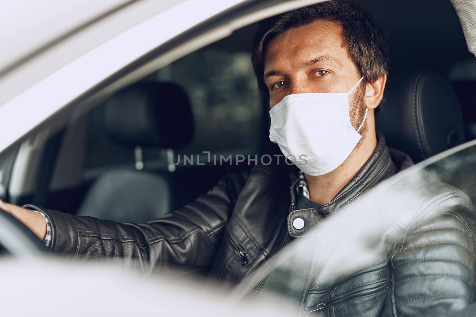 Young man driving car in medical mask, portrait