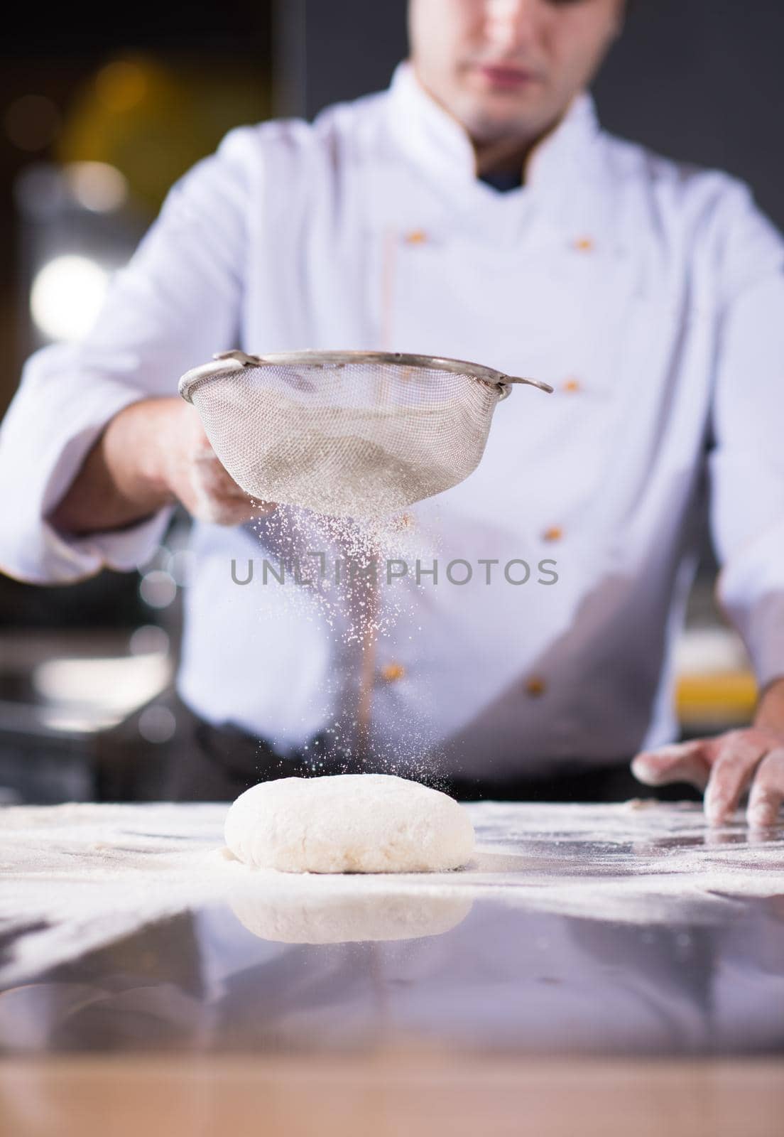 chef sprinkling flour over fresh pizza dough by dotshock