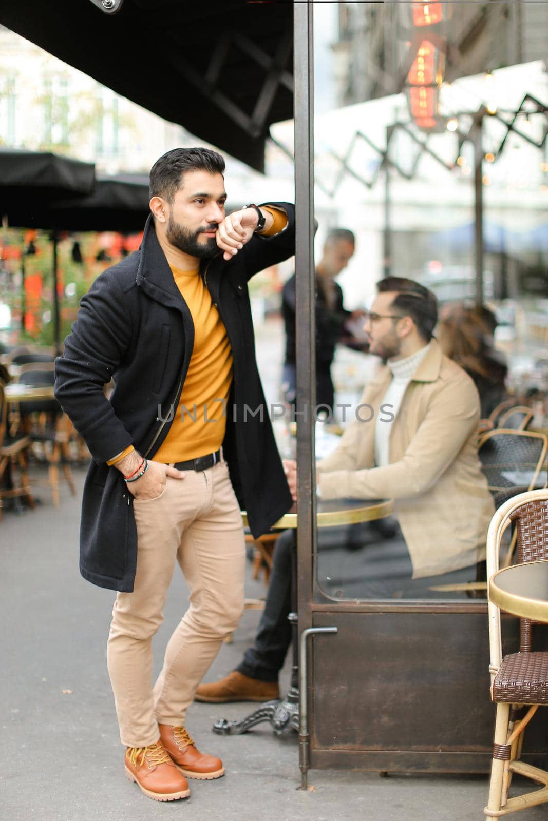 Young fashionable european man standing at street cafe outdoors. Concept of life style and male fashion.