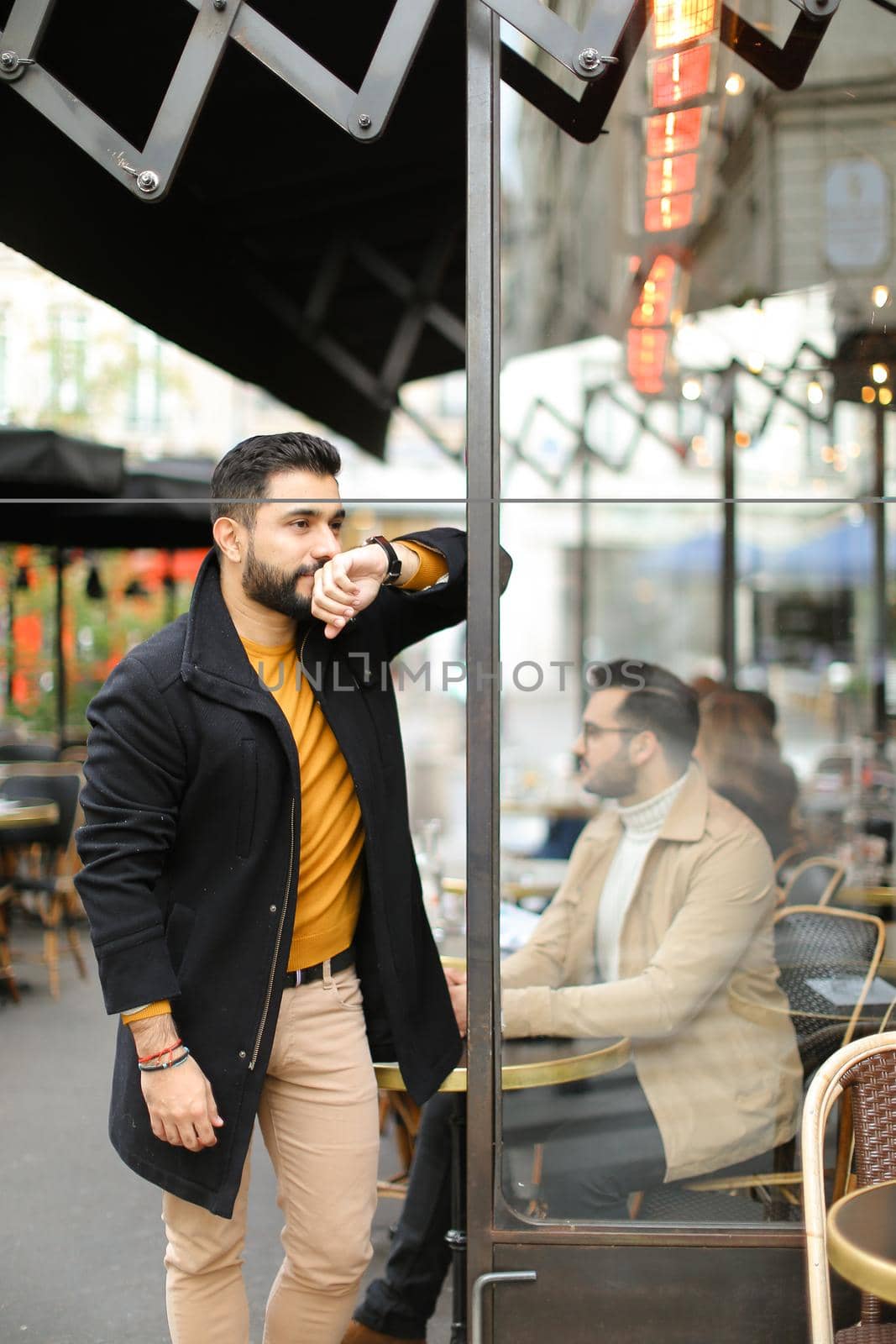 Young fashionable caucasian man standing at street cafe outdoors. Concept of life style and male fashion.