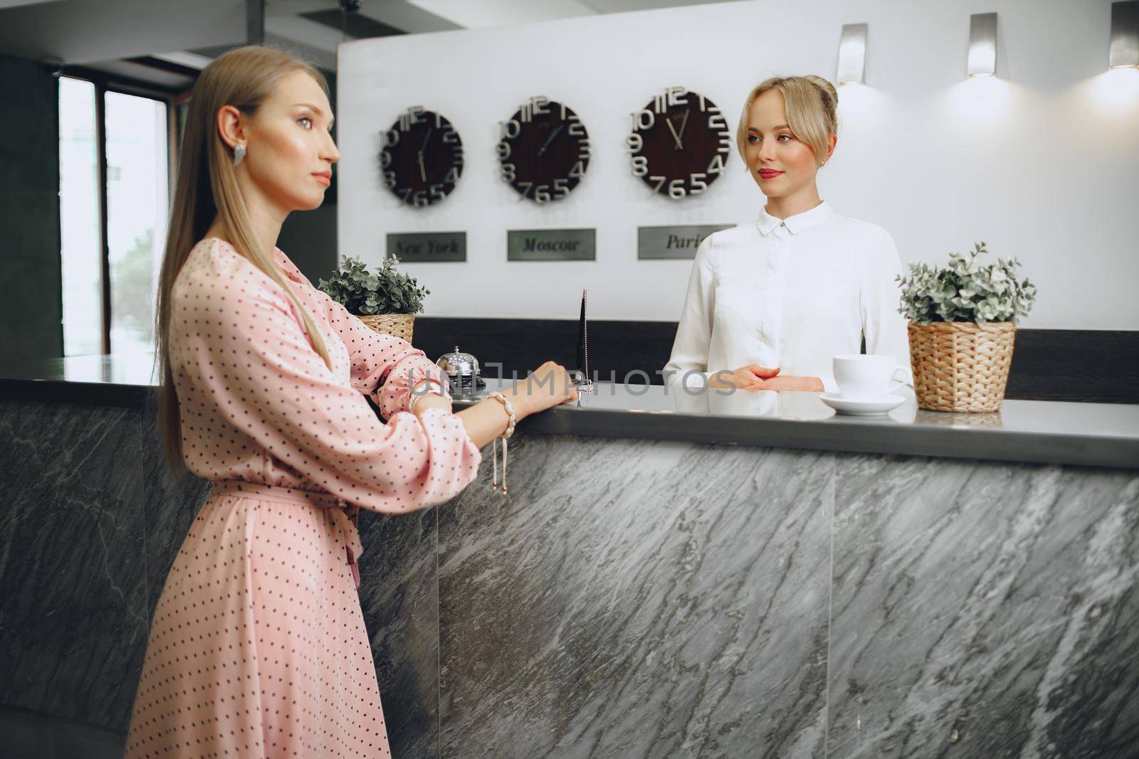 Blonde woman hotel guest checking-in at front desk in hotel by Fabrikasimf