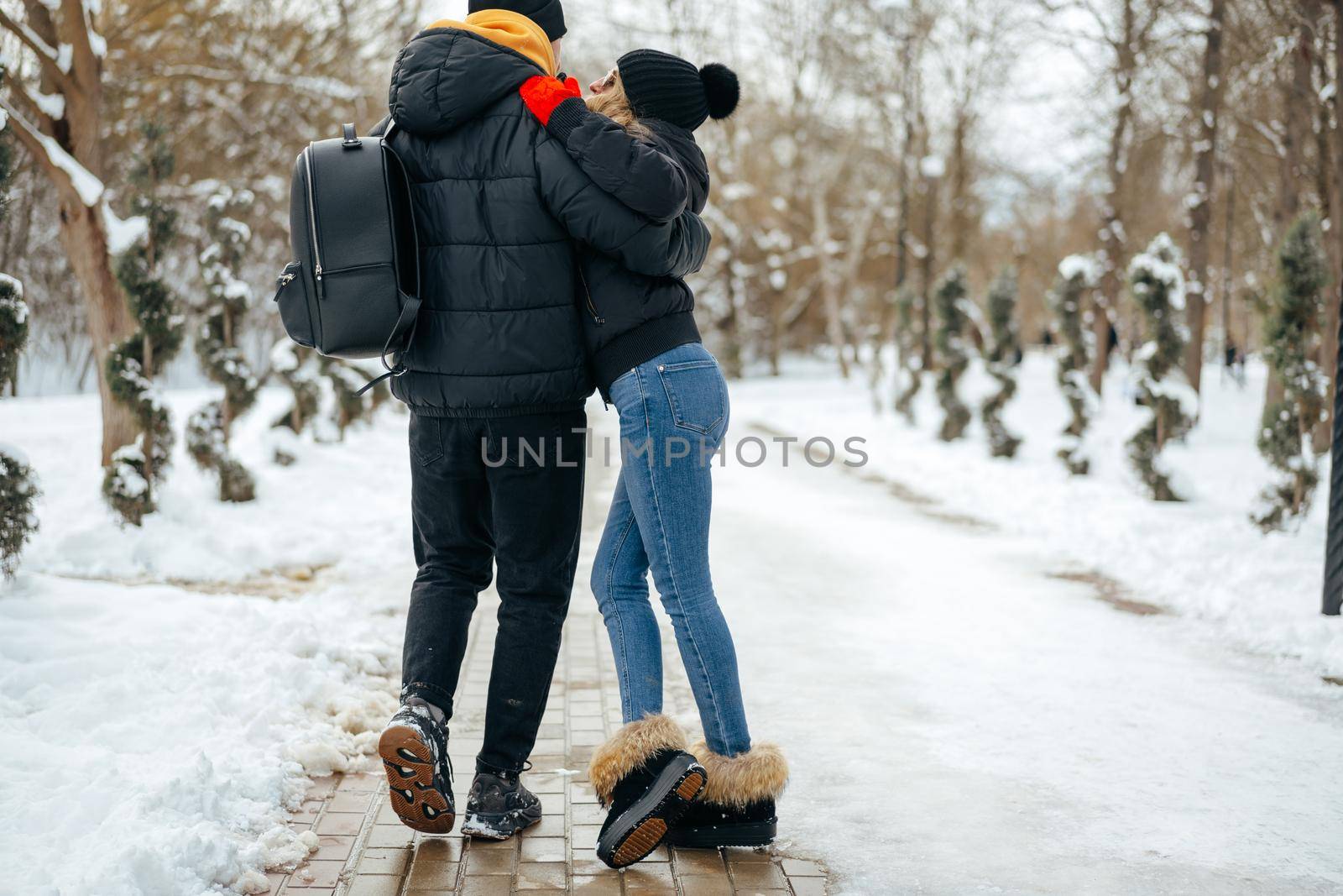 Young happy smiling couple in love having a walk in a winter park
