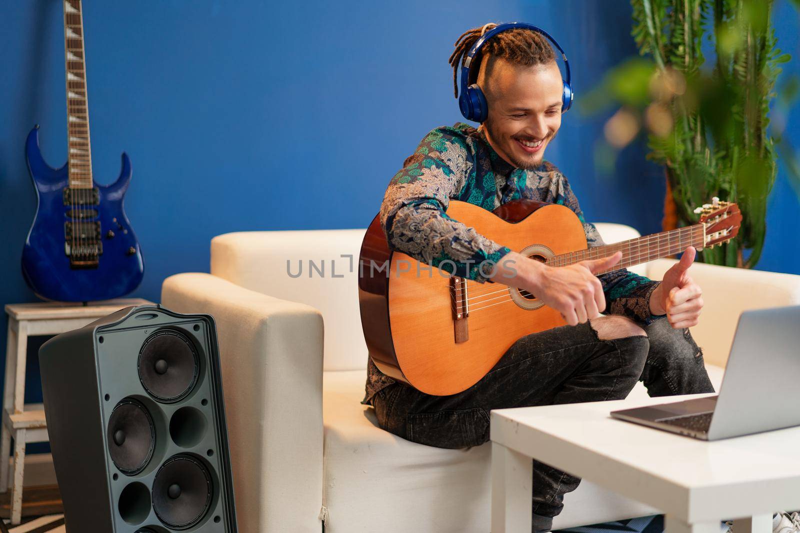 Young man sitting in his room and watching guitar tutorial on laptop close up