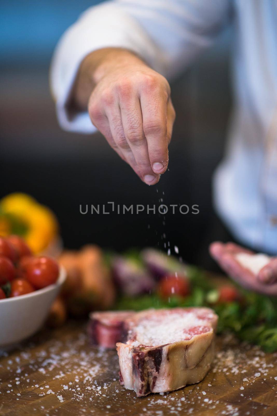 Chef putting salt on juicy slice of raw steak by dotshock