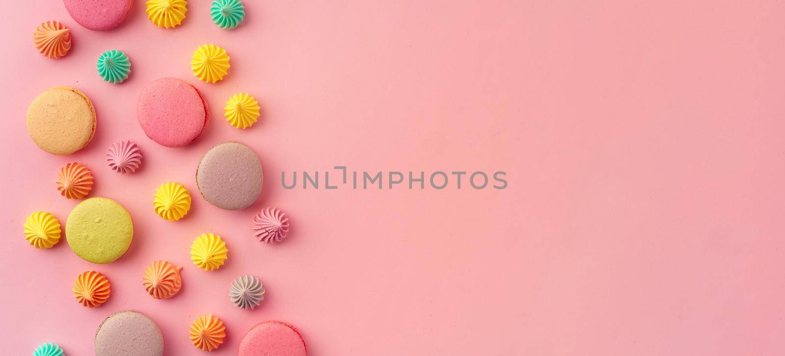 Pile of colorful macaroon cookies on pink background close up