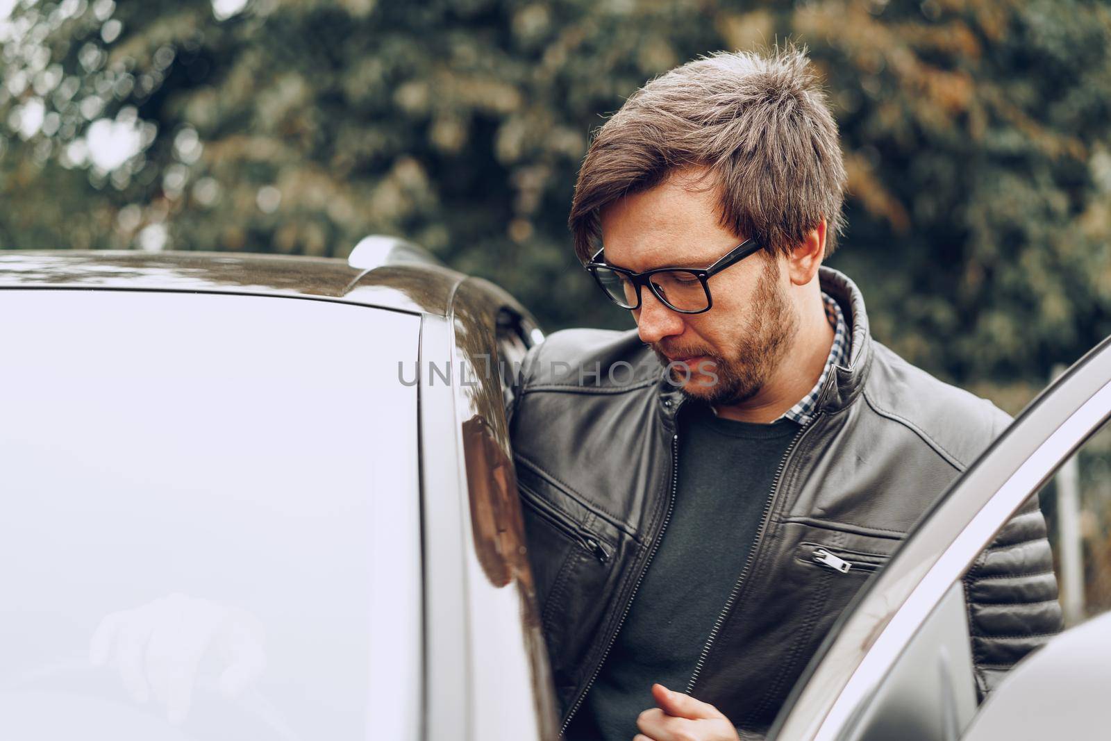 Stylish man in glasses sits in a car, close up portrait