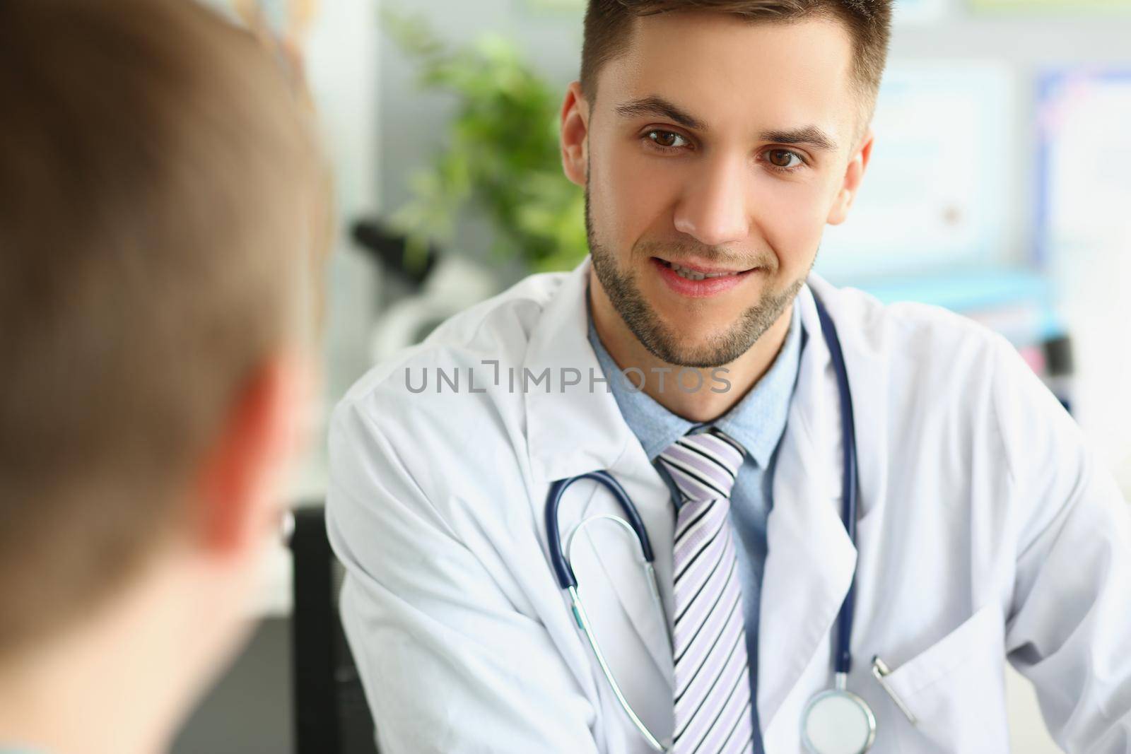 Young male doctor listens to a patient, close-up face by kuprevich
