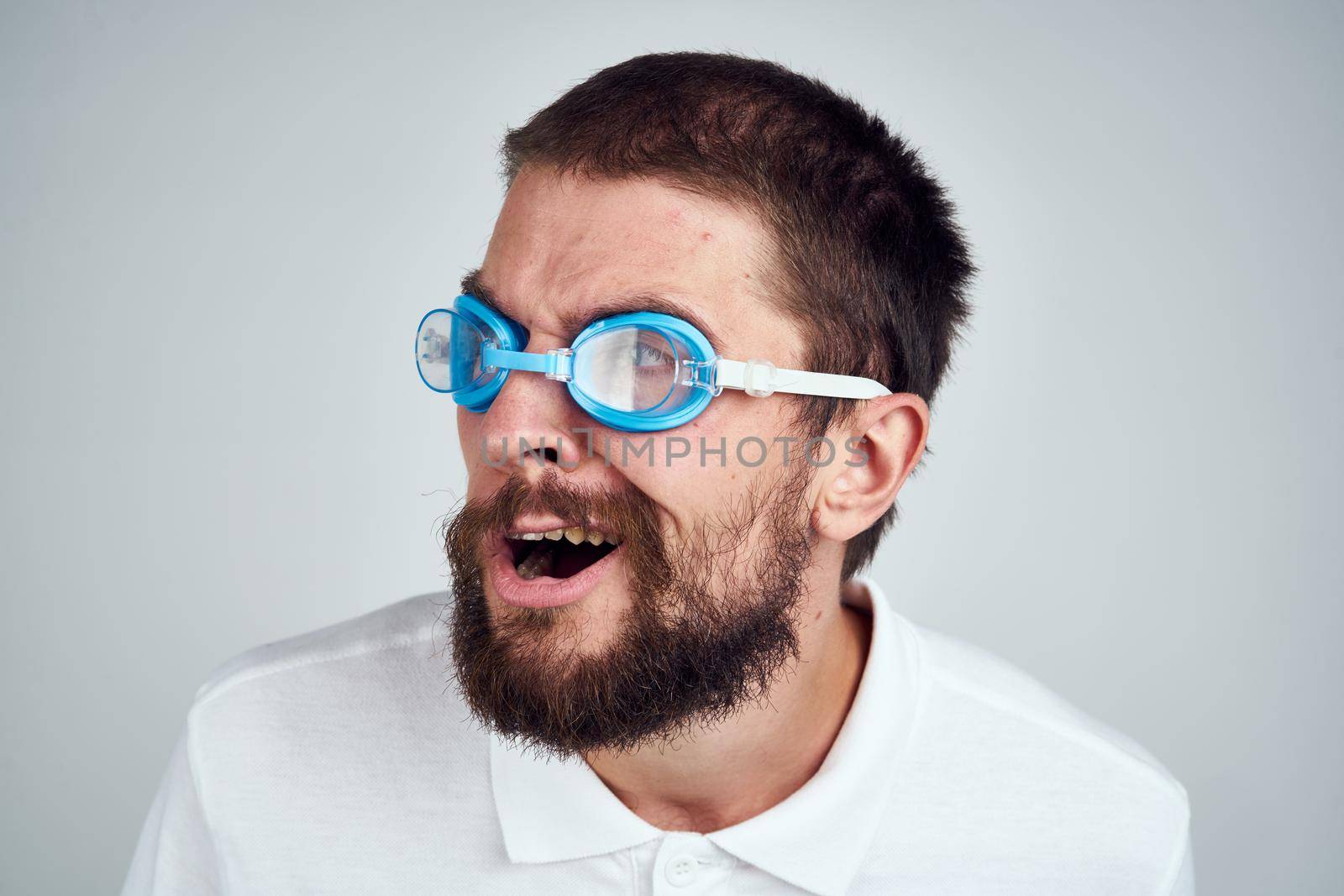 bearded man white shirt goggles for swimming light background. High quality photo