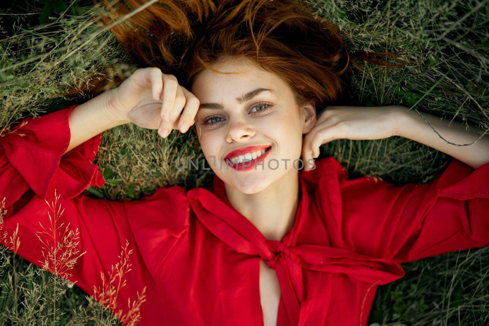 woman in red dress lies on the grass top view freedom. High quality photo